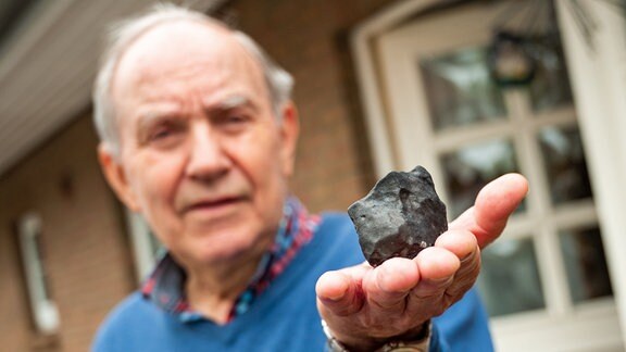 Wilfried Labusch, Hausbesitzer, hält vor seinem Haus einen kleinen Meteoriten, der niedergegangen ist.