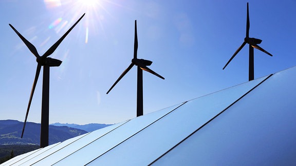 Symbolbild Energiewende: Solardach mit Windkraftanlagen im Hintergrund
