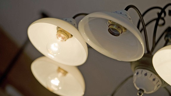 Altmodische Deckenlampe mit leuchtenden Glübirnen, eine fehlende Birne, Ansicht von schräg unten, Ästhetik durch Unschärfe des hinteren Lampenteils