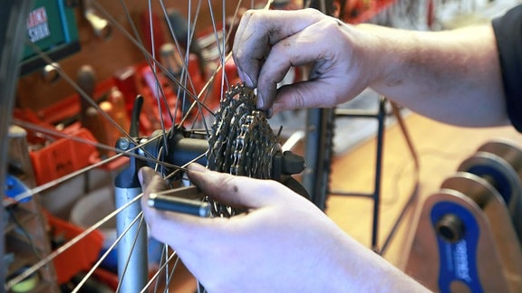 Ein Mann hängt eine Fahrradkette auf die Zahnräder.