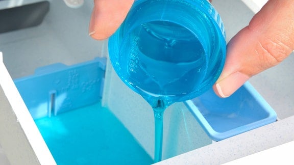 Flüssigwaschmittel wird in das Waschmittelfach einer Waschmaschine gegeben.