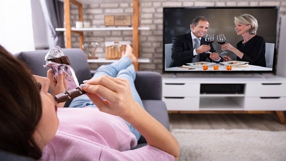 Junge Frau isst auf einer Couch Schokolade und sieht Fernsehen