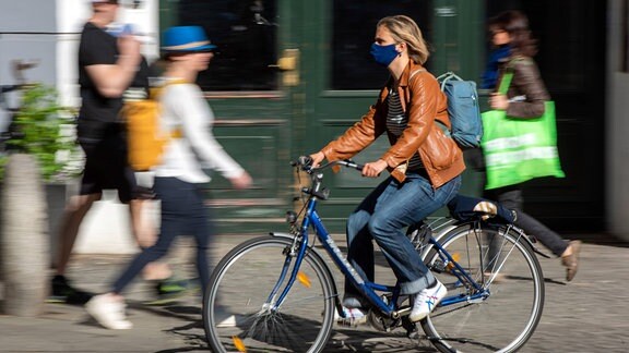 Fahrradfahrerin mit Mund-Nasen-Maske unterwegs im Berliner Stadtteil Prenzlauer Berg