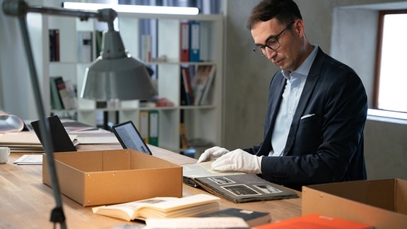 Dr. Stefan Hördler mit Album an Schreibtisch