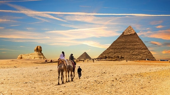 Touristen auf Kamelen vor den Pyramiden von Gizeh