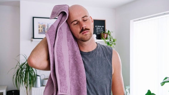 Mann reibt seinen kahlen Kopf mit einem Handtuch.