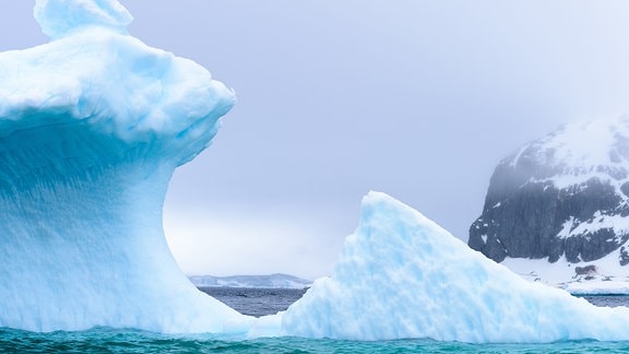 Blau-weißer Eis-Gletscher mit Bogen-förmiger Aushölung am Meer in Antarktis
