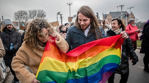 Demonstranten entrollen eine Regenbogenflagge während der Frauendemonstration.