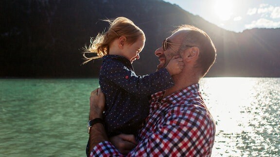 Vater mit kleinem Mädchen auf dem Arm an einem See