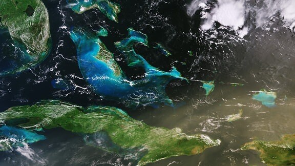 Satellitenaufnahme der Karibik um Kuba, auf der deutlich rote Staubpartikel zu sehen sind. 