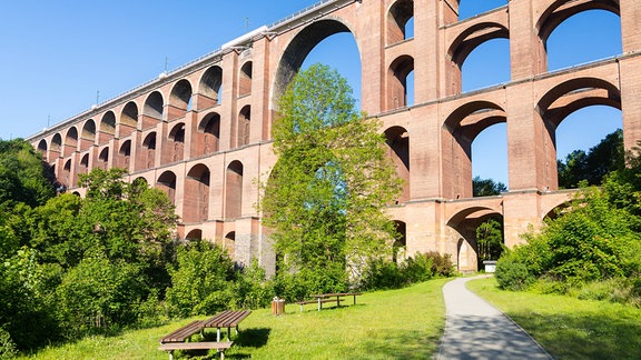 Sitzbänke stehen vor einer imposanter Brücke