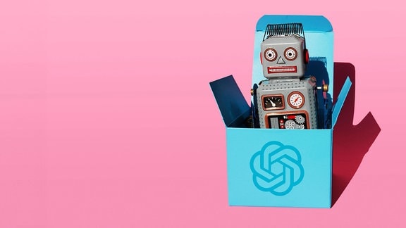 Stereotyper Spielzeugroboter schaut aus geöffneter würfelförmiger Box auf der sich das Logo von Open AI befindet