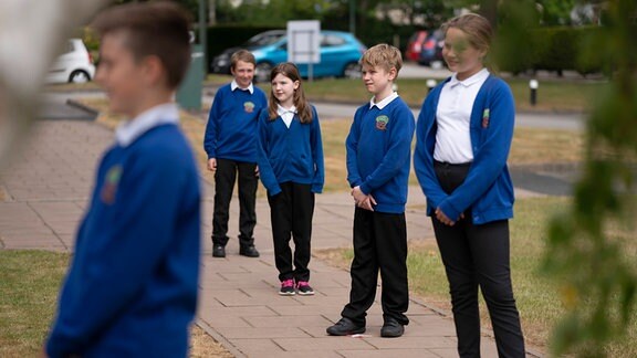 Britische Grundschüler in Schuluniformen stehen mit Abstand in einer Reihe