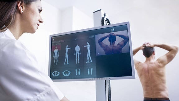 Ärztin schaut bei der Untersuchung eines Patienten auf einer Monitor.