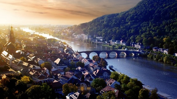 Heidelberg von oben: Flache Altstadt im Flußtal, Fluß Neckar, seitlich nach hinten abfallender Hügel, blaue Stunde mit untergehender Sonne, dramatische Farben