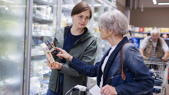Eine junge Frau hilft beim einkaufen einer älteren Frau.