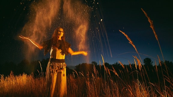 Eine Frau steht nachts auf einem Feld