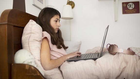 Ein Mädchen mit Laptop im Bett
