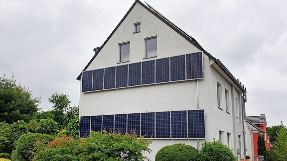 Mehrfamilienhaus mit horizontalen Sonnenkollektoren an der Hauswand.