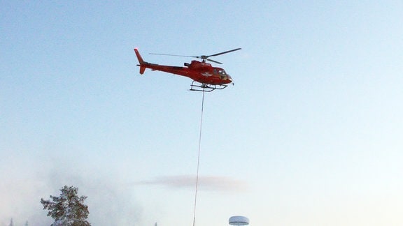 Ein Helikopter hat den an einem Fallschirm auf den Boden zurückgekehrten Transportbehälter mit den Experimenten eingesammelt und fliegt ihn zurück zur Raketenbasis in Esrange.