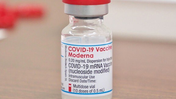 Eine Ampulle des Moderna Covid-19-Impfstoffs steht auf einem Tisch.