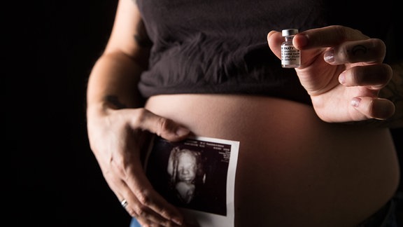 Eine schwangere Frau mit Babybauch hat eine Impfdosis mit dem mRNA-Impfstoff Comirnaty