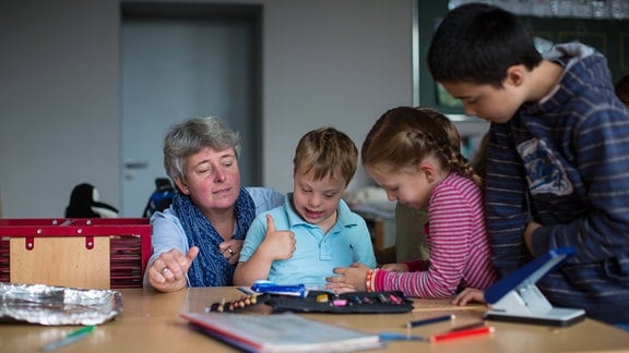 Inklusionshelferin kümmert sich um Schüler mit Down Syndrom in einer Integrationsklasse an einer Grundschule