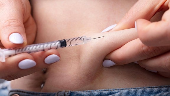 Eine Frau injiziert sich Insulin in den Bauch.