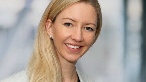 Porträtfoto von Professorin Isabel Brandhorst vom Universitätsklinikum Tübingen. Isabell Brandhorst lächelt, hat lange, blonde Haare und trägt ein hellgraues Jacket sowie ein schwarzes T-Shirt.