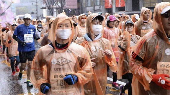 Läufer tragen bei einem Marathon in Kumamoto Atemschutzmasken 