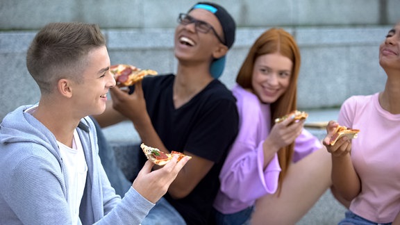Jugendliche essen Pizza und freuen sich