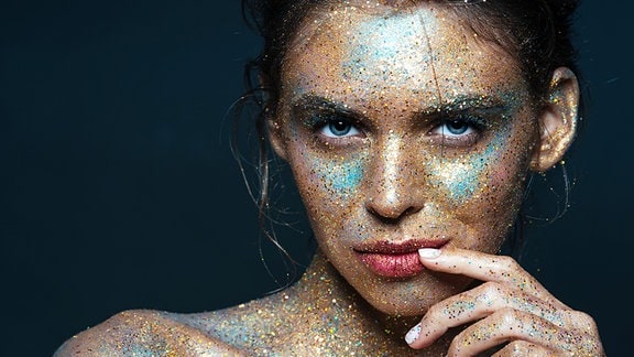 Eine junge Frau mit Farbpunkten im Gesicht
