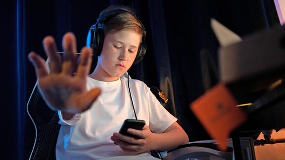 Ein Junge mit Smartphone und Kopfhörern