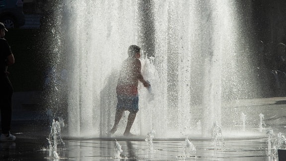 Ein kind läuft durch einen Springbrunnen.