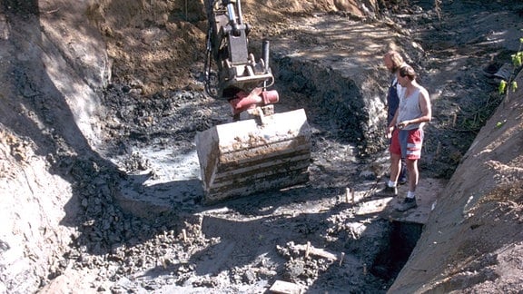 Zwei Männer vor einer Baggerschafel im Loch einer Ausgrabung in Schweden 