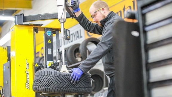 Kfz-Mechatroniker montiert einen Reifen