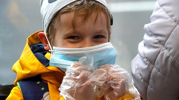 EIn Kind mit Schutzmaske und Handschuhen in der Moskauer Metro.