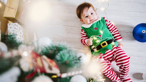 Kostümiertes Kleinkind mit elektrischer Weihnachtsbeleuchtung