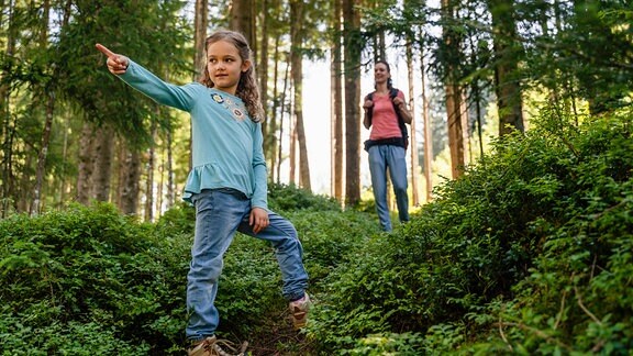 Ein Mädchen und seine Mutter wandern in einem Wald.