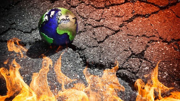Symbolfoto Klimawandel und Klimakatastrophe - Erdkugel und Flammen auf gebrochenem Grund