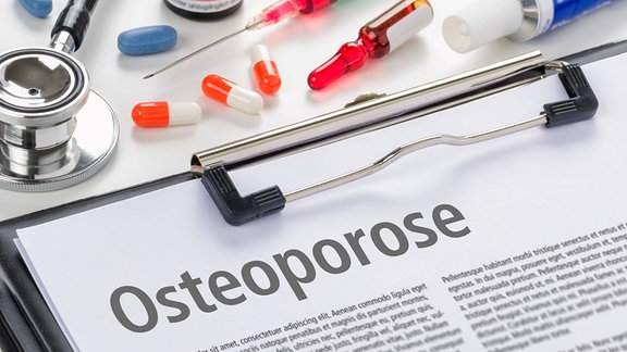 Klemmbrett mit Schriftstück, das den Schriftzug 'Osteoporose' zeigt, darüber Spritze und Pillen