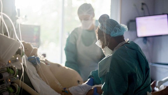 Pflegekräfte bei einem Patienten am Bett im Krankenhaus.