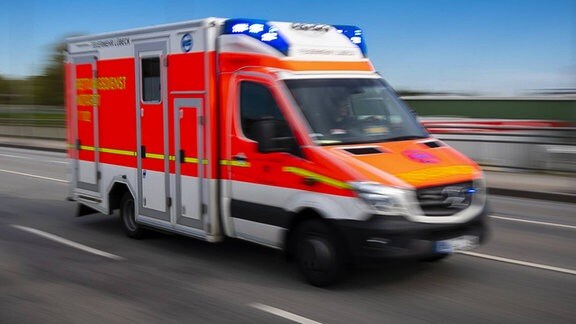 Ein Krankenwagen fährt mit Blaulicht über eine Brücke.