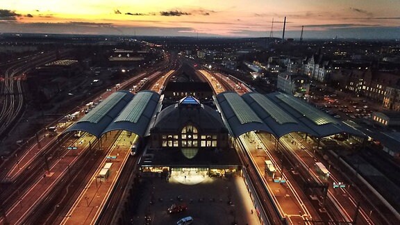 Hauptbahnhof Halle Saale von oben bei Dämmerung und Sonnenuntergang. Zentrales historisches Gebäude mit zwei Plattformen links und drei rechts.