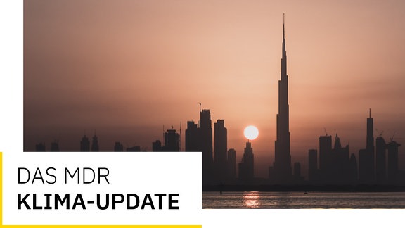 Stimmungsvolle dunkle Silhouette von Dubai bei Sonnenuntergang, Dunst und gelb-rosafarbenes Licht. Text: Das MDR Klima-Update
