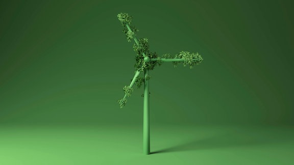 Grünes Windradmodell mit kleinen grünen Blättern auf Rotor vor grünem Hintergrund