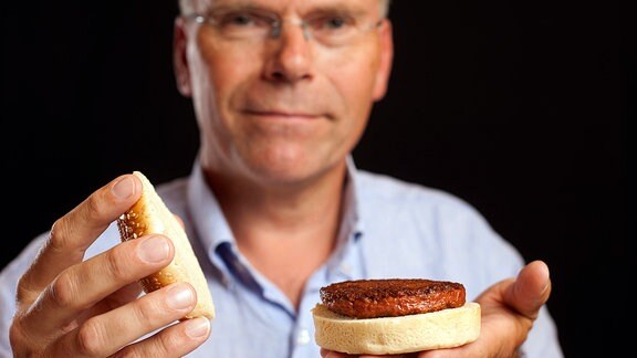 Professor Mark J Post mit seinem Labor-Burger. In fünf Jahren, verspricht er, kann den sich jeder leisten.