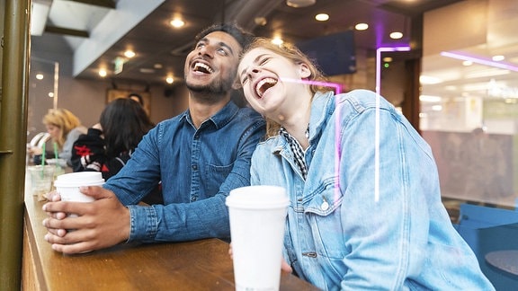 Zwei junge Menschen lachen in einem Café