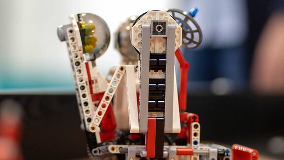 Ein Legoroboter mit langem ausklappbaren Arm.