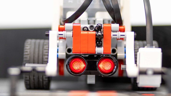 An einem Legoroboter mit Rädern sind Drähte befestigt.